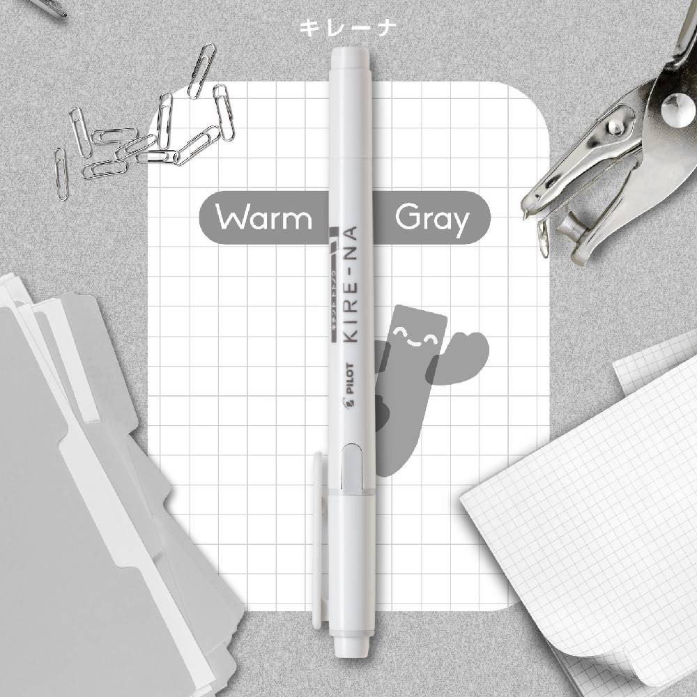 White pen with 'KIRE-NA' branding on a gray surface with stationery items.